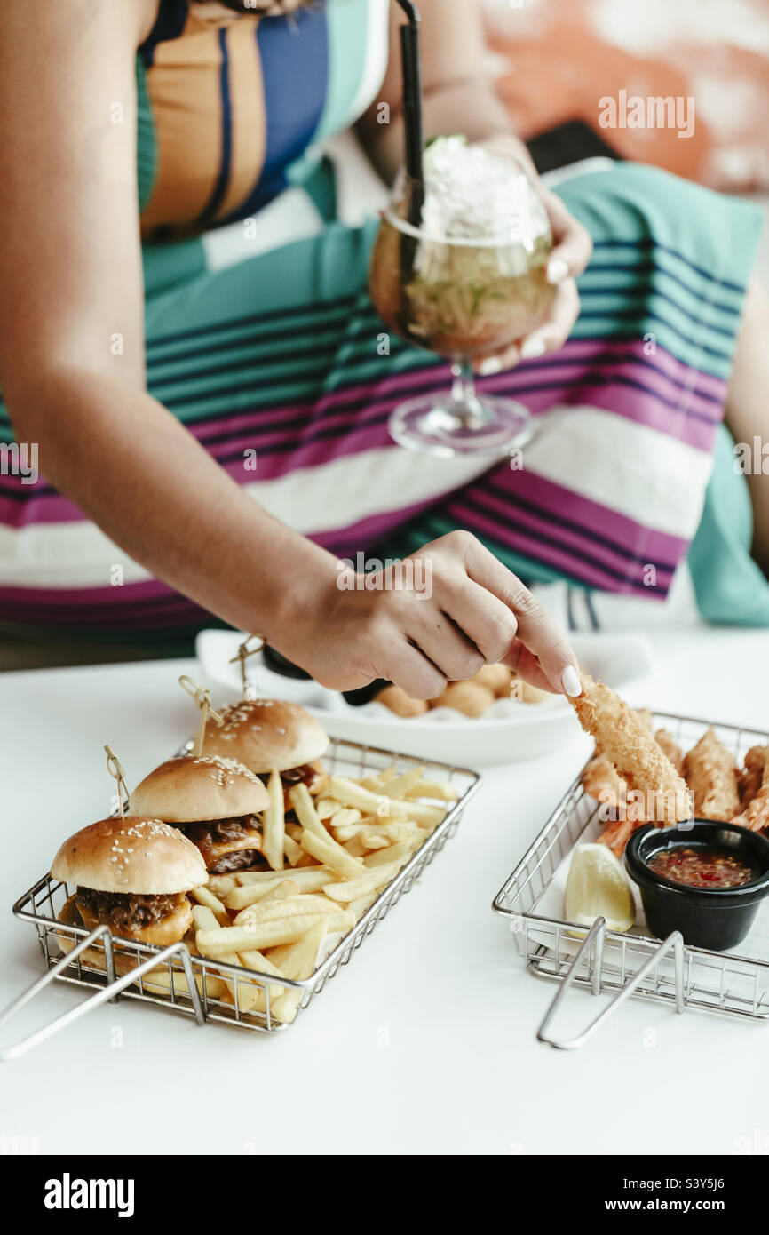Woman having a snack and a cocktail, hands only in frame Stock Photo