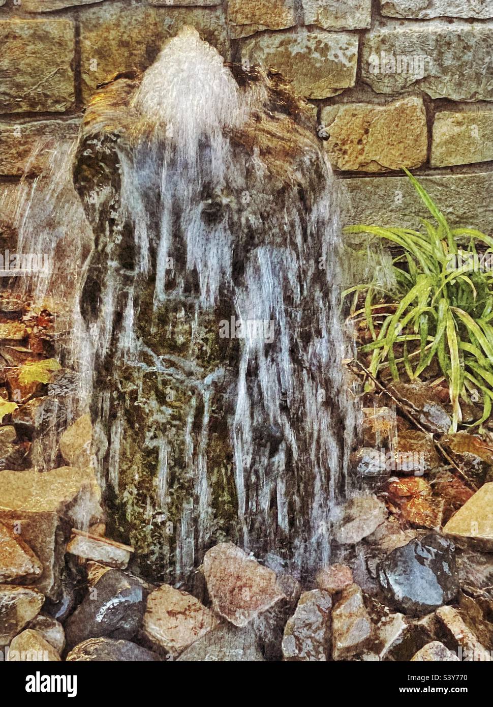 A small decorative water fountain on the grounds of Gardner Village in the Salt Lake valley of Utah, USA. The bubbling fountain and water flow have been frozen in camera, making interesting patterns. - Smartphone Captured Stock Image