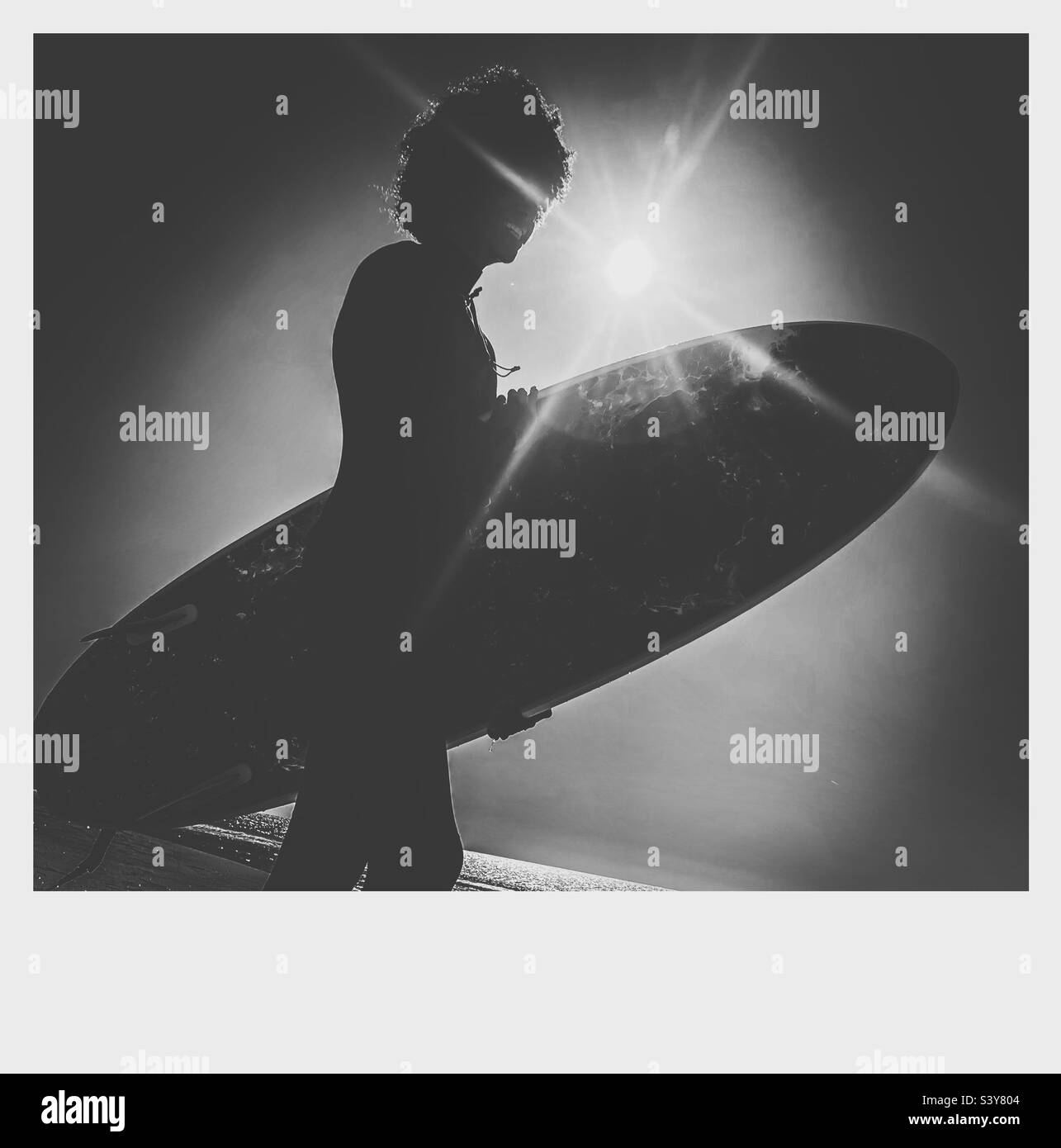 Young surfer and surf board with morning sun lens flare Stock Photo Alamy