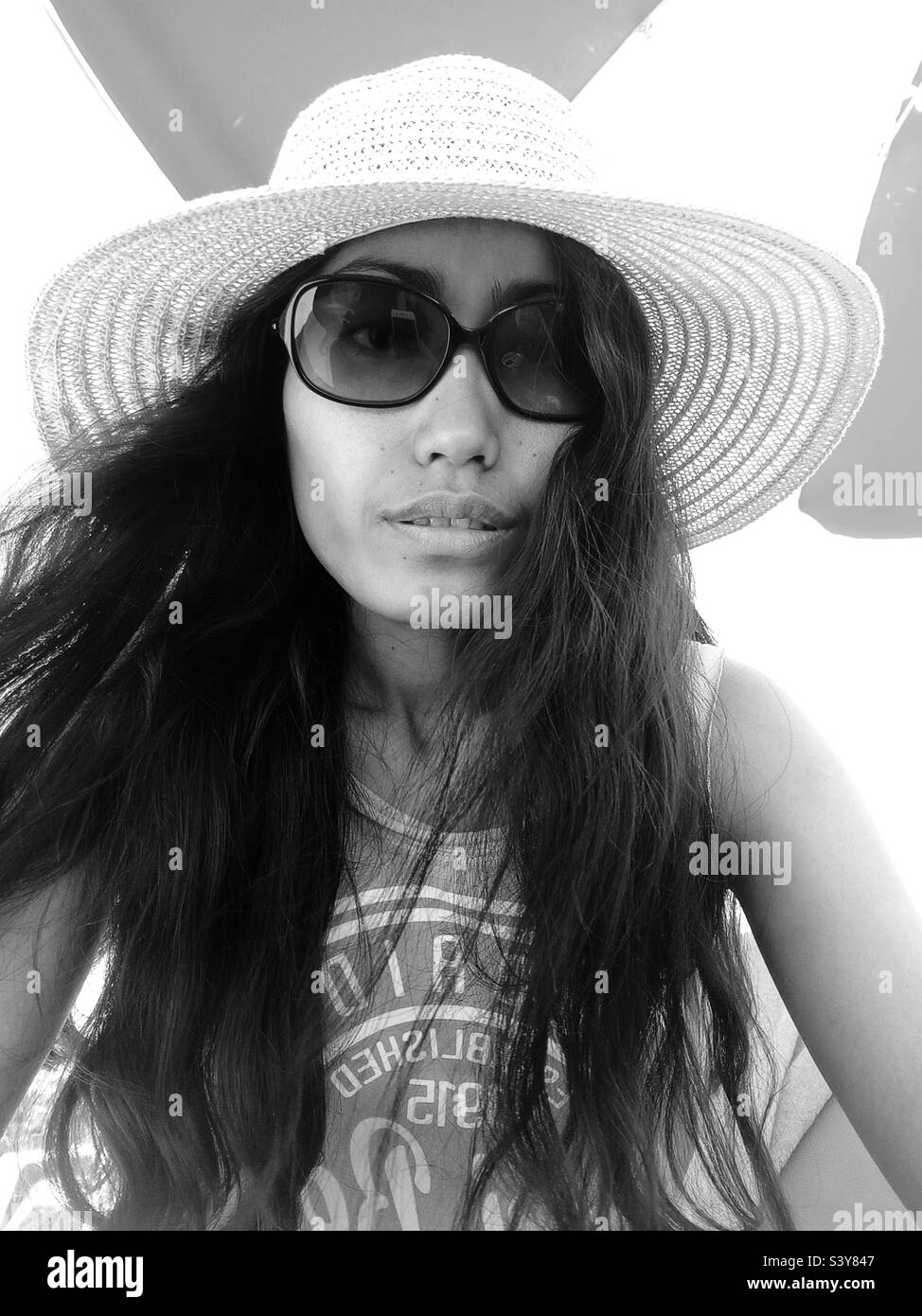 A woman wearing a hat and with a long hair in black and white - Smartphone Captured Stock Image