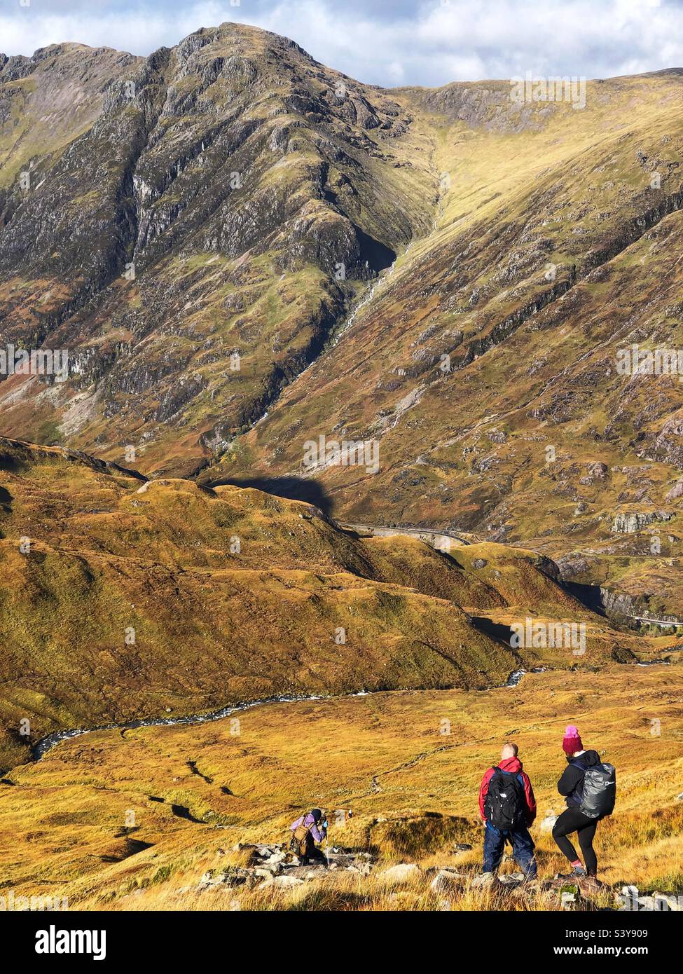 Walkers on the path and slopes of Munro Buachaille Etive Beag, with a view towards the ridge of Aonach Eagach ridge, Glencoe, Scotland - Smartphone Captured Stock Image