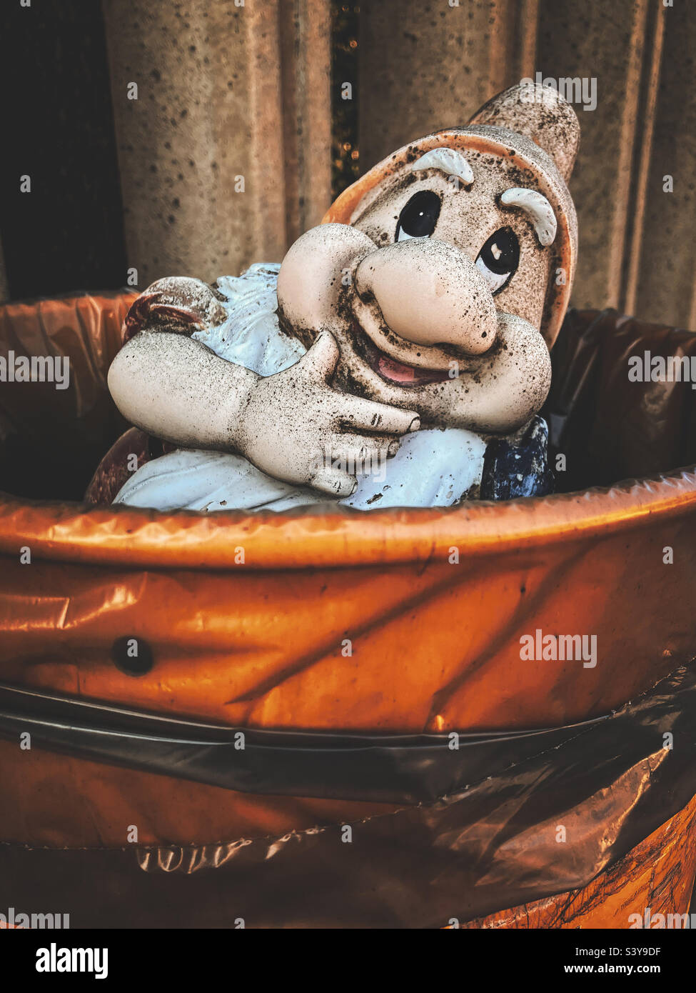 Garden gnome in a rubbish bin, Silvi Marina, Italy Stock Photo