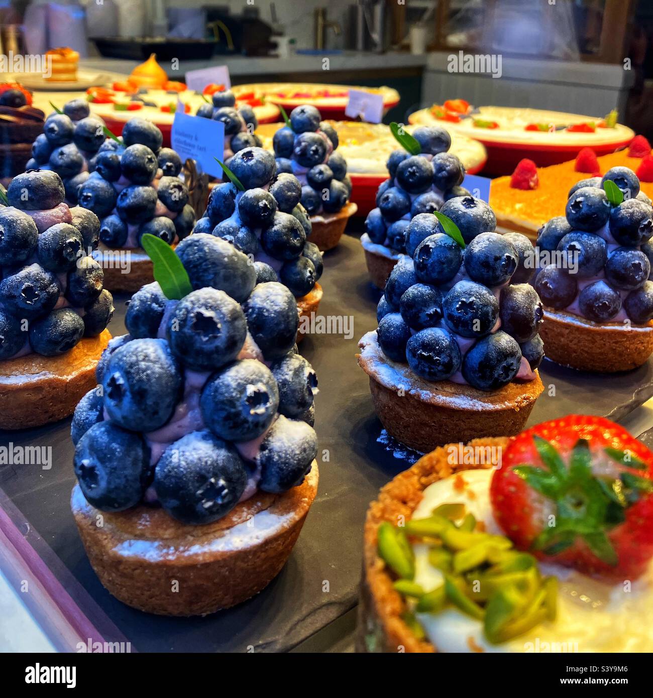 Blueberry tartlets and other cakes in the window of a cafe patisserie Stock Photo