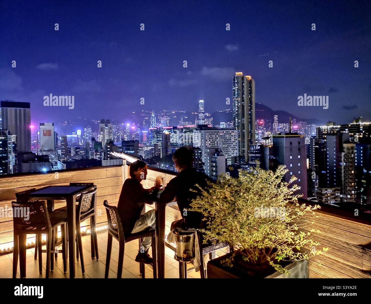A couple enjoying the stunning city views from the Madera hotel rooftop bar, Kowloon,Hong Kong. - Smartphone Captured Stock Image