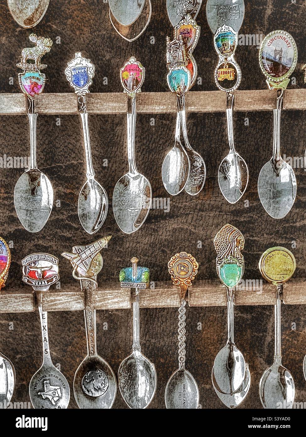 A spoon collection, in a display case filled beyond capacity, that is made up of spoons from many cities, countries and landmarks. Grunge and HDR effects digitally added via IOS app Snapseed. - Smartphone Captured Stock Image