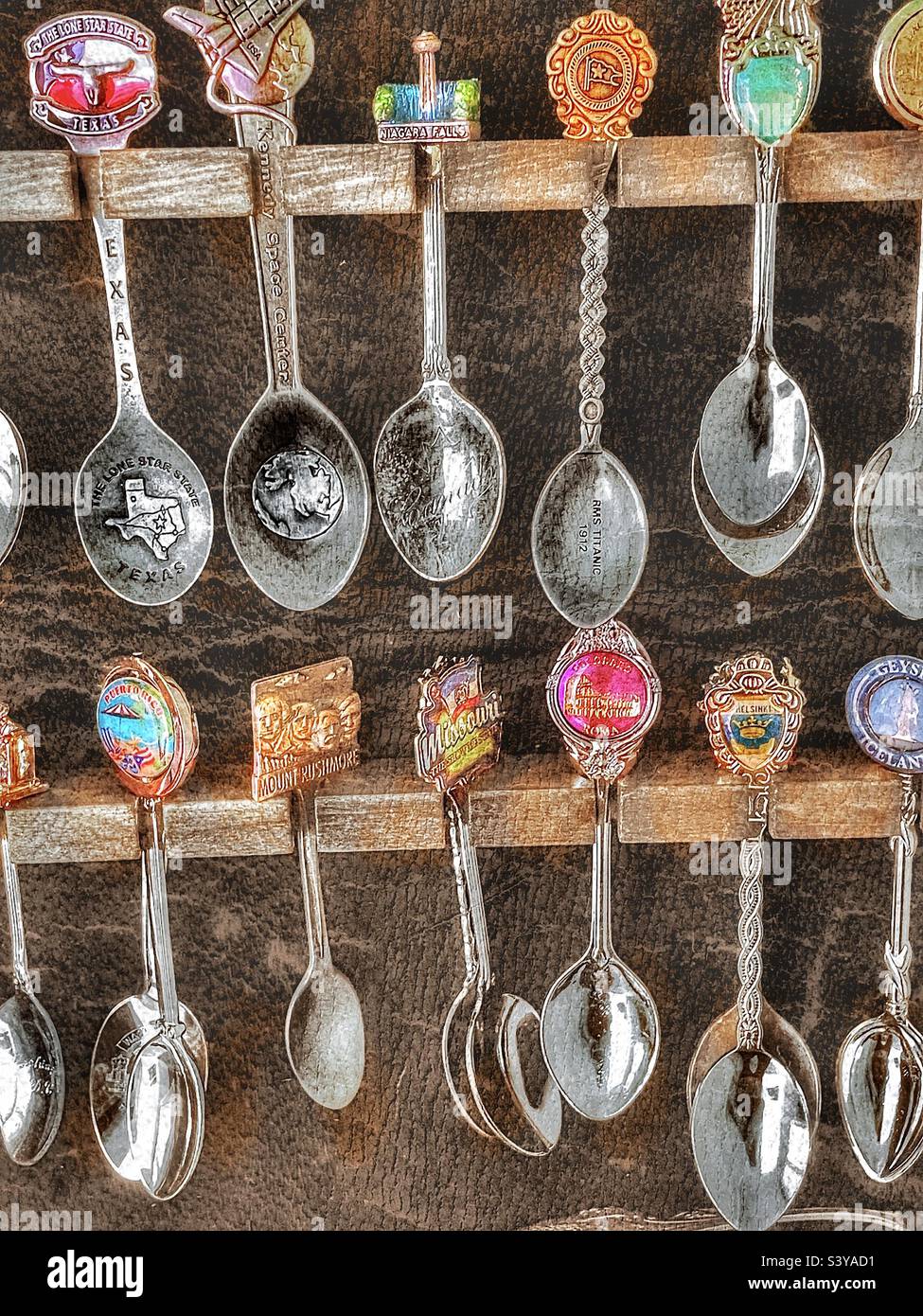 A spoon collection, in a display case filled beyond capacity, that is made  up of spoons from many cities, countries and landmarks. Grunge and HDR  effects digitally added via IOS app Snapseed
