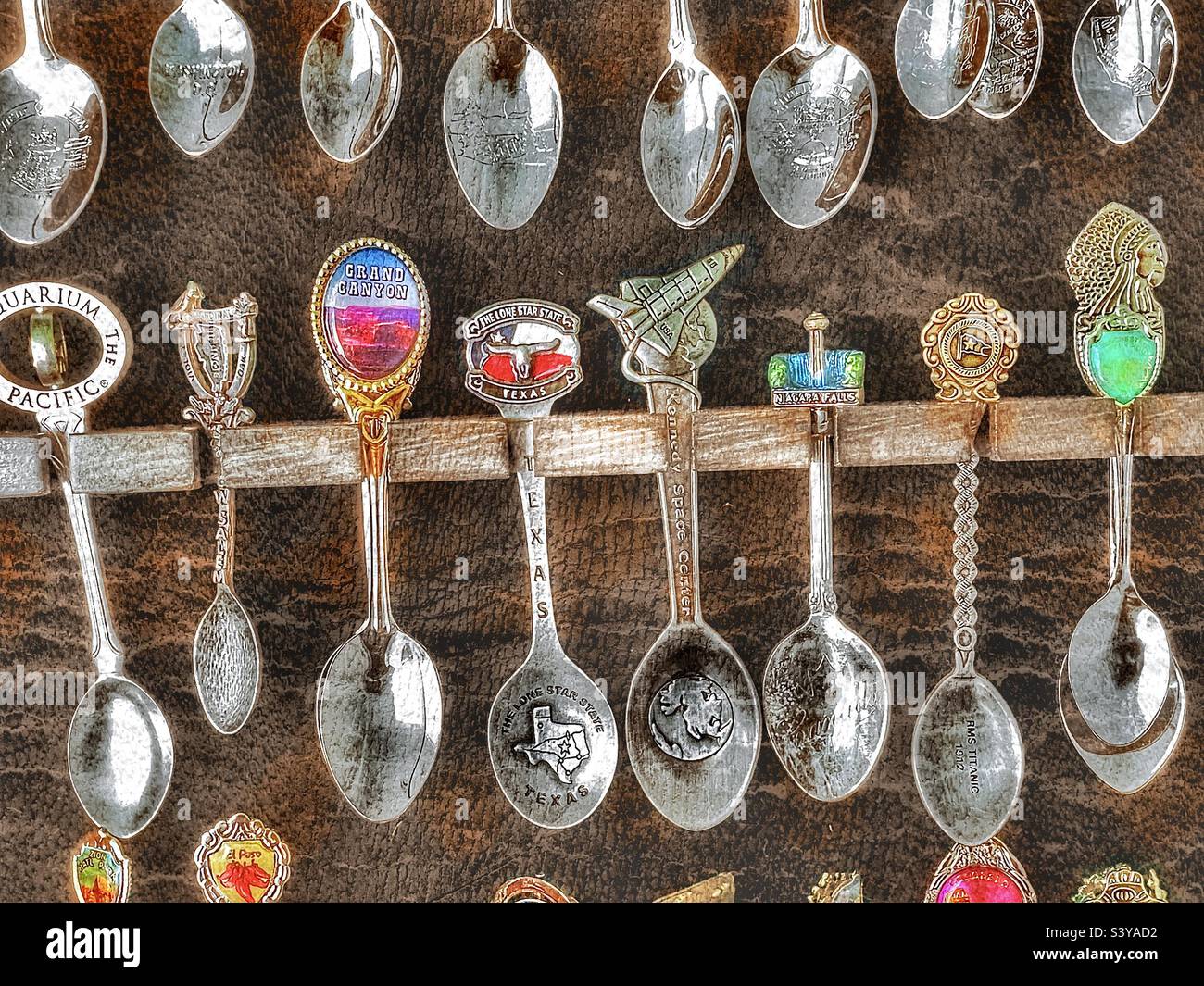 A spoon collection, in a display case filled beyond capacity, that is made up of spoons from many cities, countries and landmarks. Grunge and HDR effects digitally added via IOS app Snapseed. - Smartphone Captured Stock Image