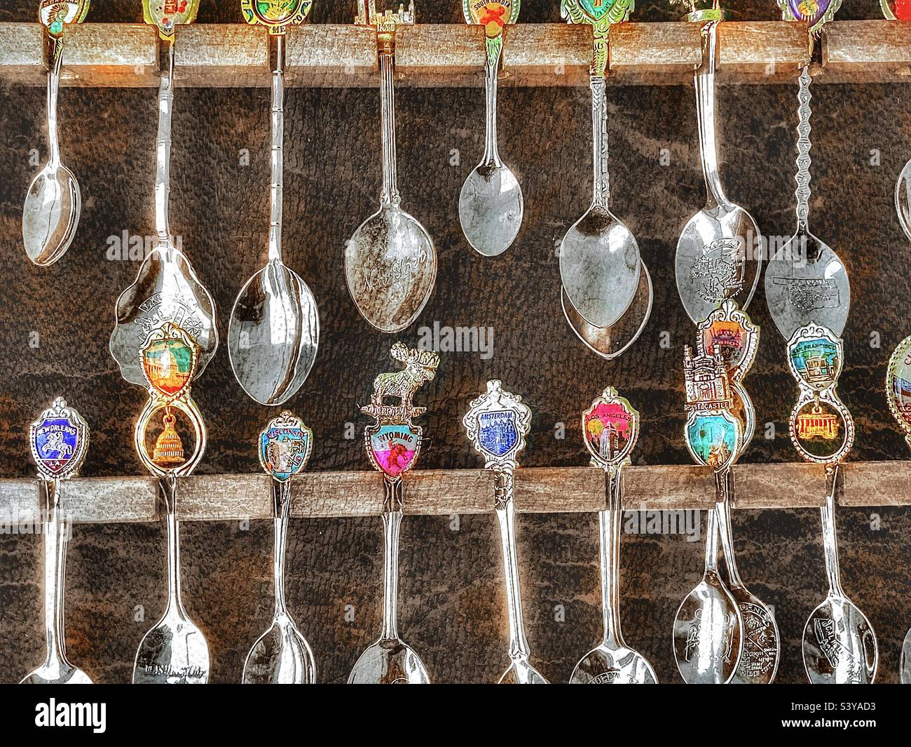 A spoon collection, in a display case filled beyond capacity, that is made up of spoons from many cities, countries and landmarks. Grunge and HDR effects digitally added via IOS app Snapseed. - Smartphone Captured Stock Image