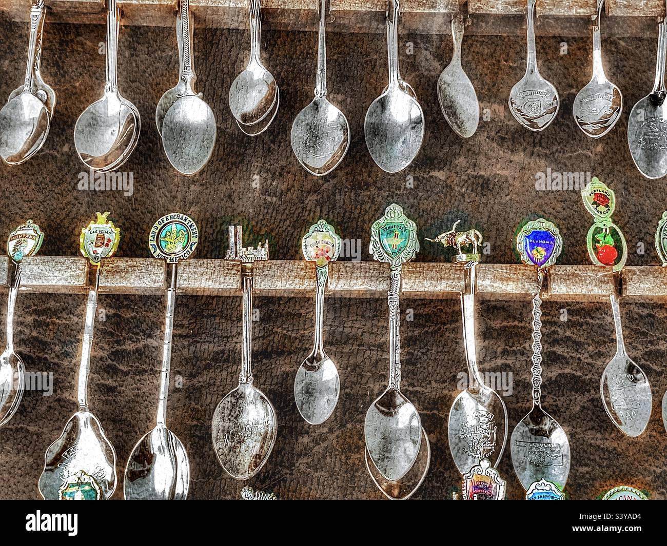 A spoon collection, in a display case filled beyond capacity, that is made up of spoons from many cities, countries and landmarks. Grunge and HDR effects digitally added via IOS app Snapseed. - Smartphone Captured Stock Image
