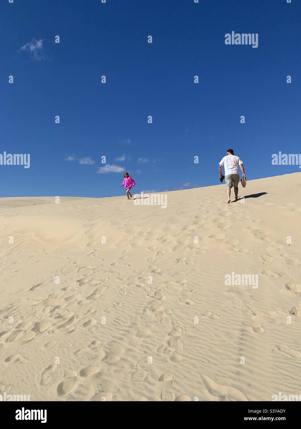 Two people walking up a sand dune - Smartphone Captured Stock Image