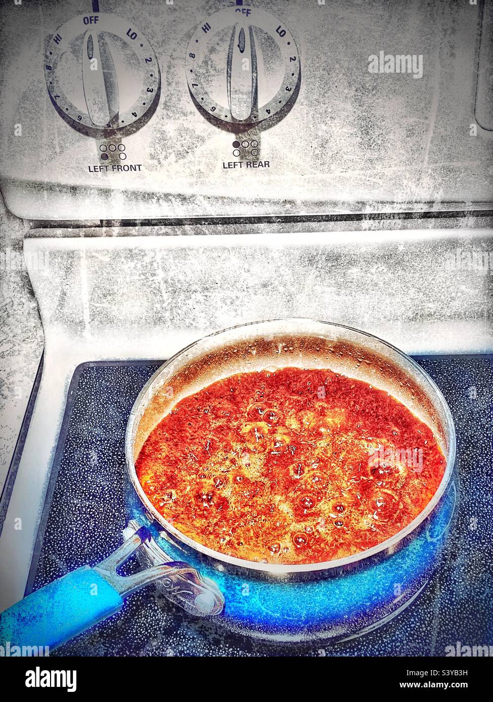 Delicious simmering brown gravy on a stovetop on Thanksgiving day in a kitchen in Utah, USA. Grunge effects added digitally for artistic reasons. Stock Photo