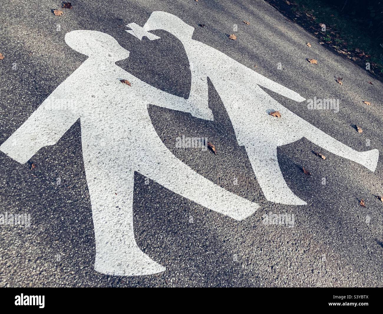 A symbol on the asphalt showing children holding hands walking signifying children crossing or a boardwalk for children - Smartphone Captured Stock Image