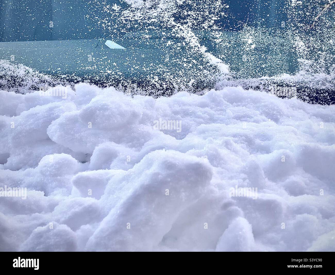 A very seasonal, wintry abstract, taken after a snowstorm in Utah, USA. The bottom two-thirds of image is snow piled up on the car’s hood, while the top third is the “mostly” cleared off windshield. - Smartphone Captured Stock Image
