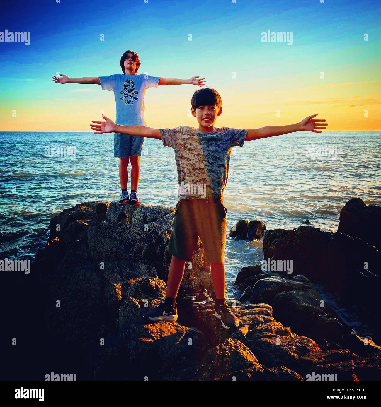 2 friends stand near the ocean and have their arms wide open - Smartphone Captured Stock Image