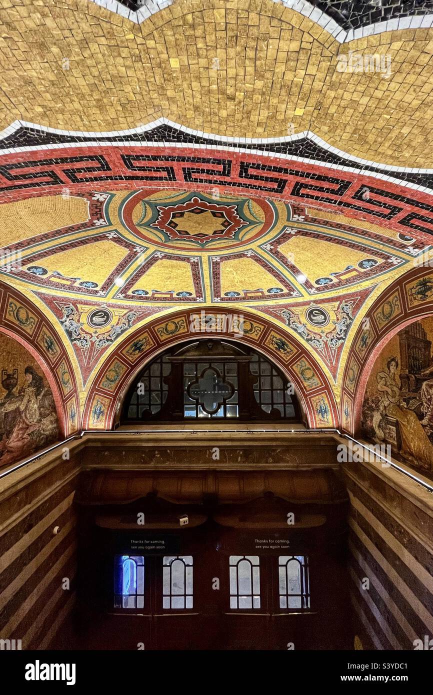 On the way out of the Coliseum theatre and opera house, London. Richly tiled ceiling and ornate decorations with wooden doors. Interior of the heritage building. - Smartphone Captured Stock Image