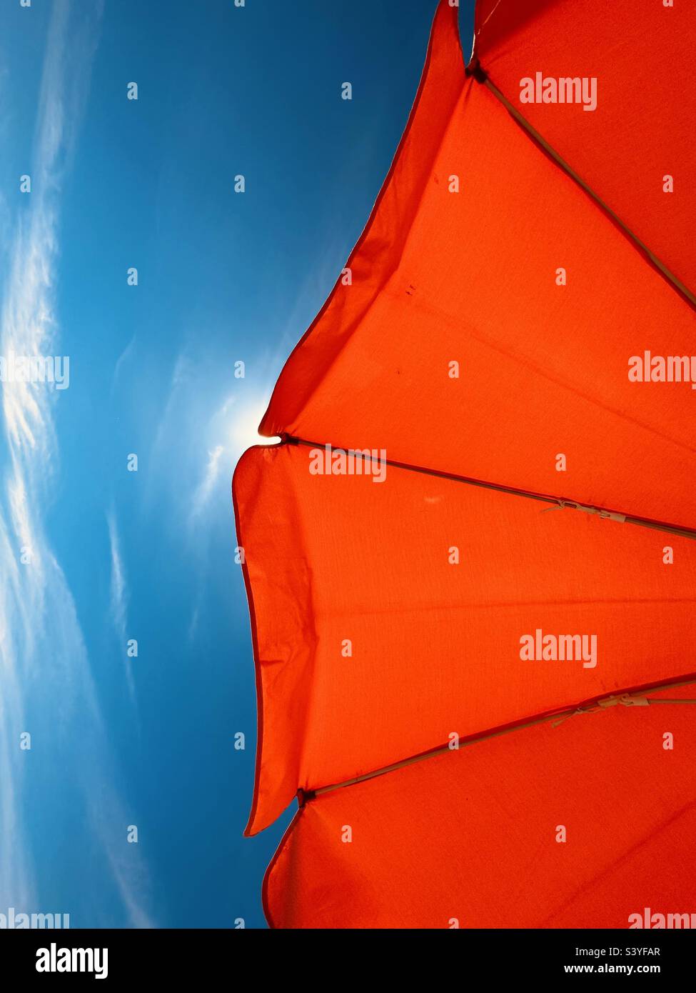 Orange beach umbrella against a blue sky Stock Photo