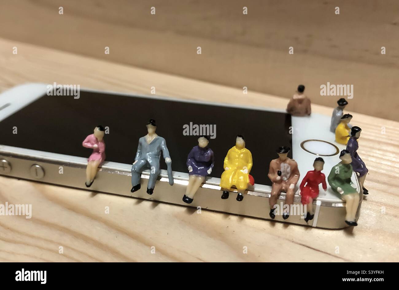 People on the phone - miniature figures sitting on an iPhone Stock Photo