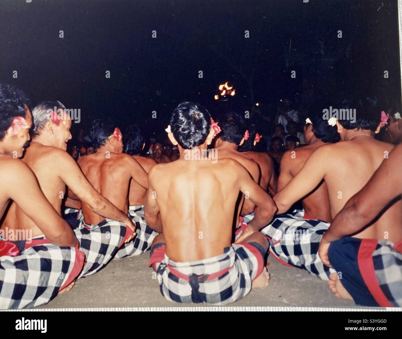 Balinese men sit in lines while perform traditional dance and song. - Smartphone Captured Stock Image