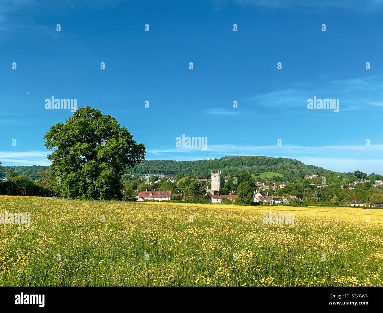 Idyllic summer buttercup field Gloucestershire landscape with Church. Upper Cam. UK. A mobile phone photo with some phone or tablet post processing. - Smartphone Captured Stock Image