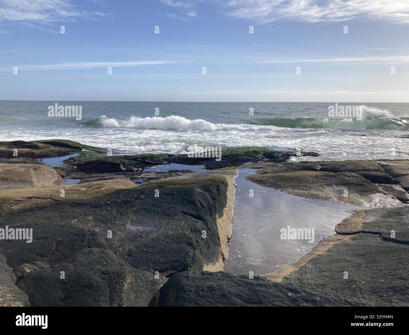 Rhode Island beach waves rolling towards large rocks on a sunny day - Smartphone Captured Stock Image
