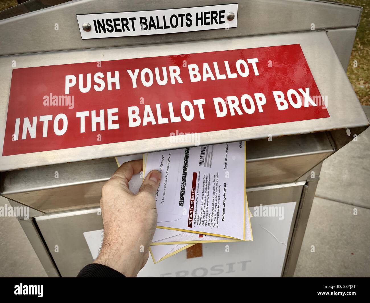 A local Ballot Drop Box, in Utah, the night before the United States midterm elections in November 2022. A person’s hand is seen depositing his family’s ballots at a local drop box on Election Day Eve Stock Photo