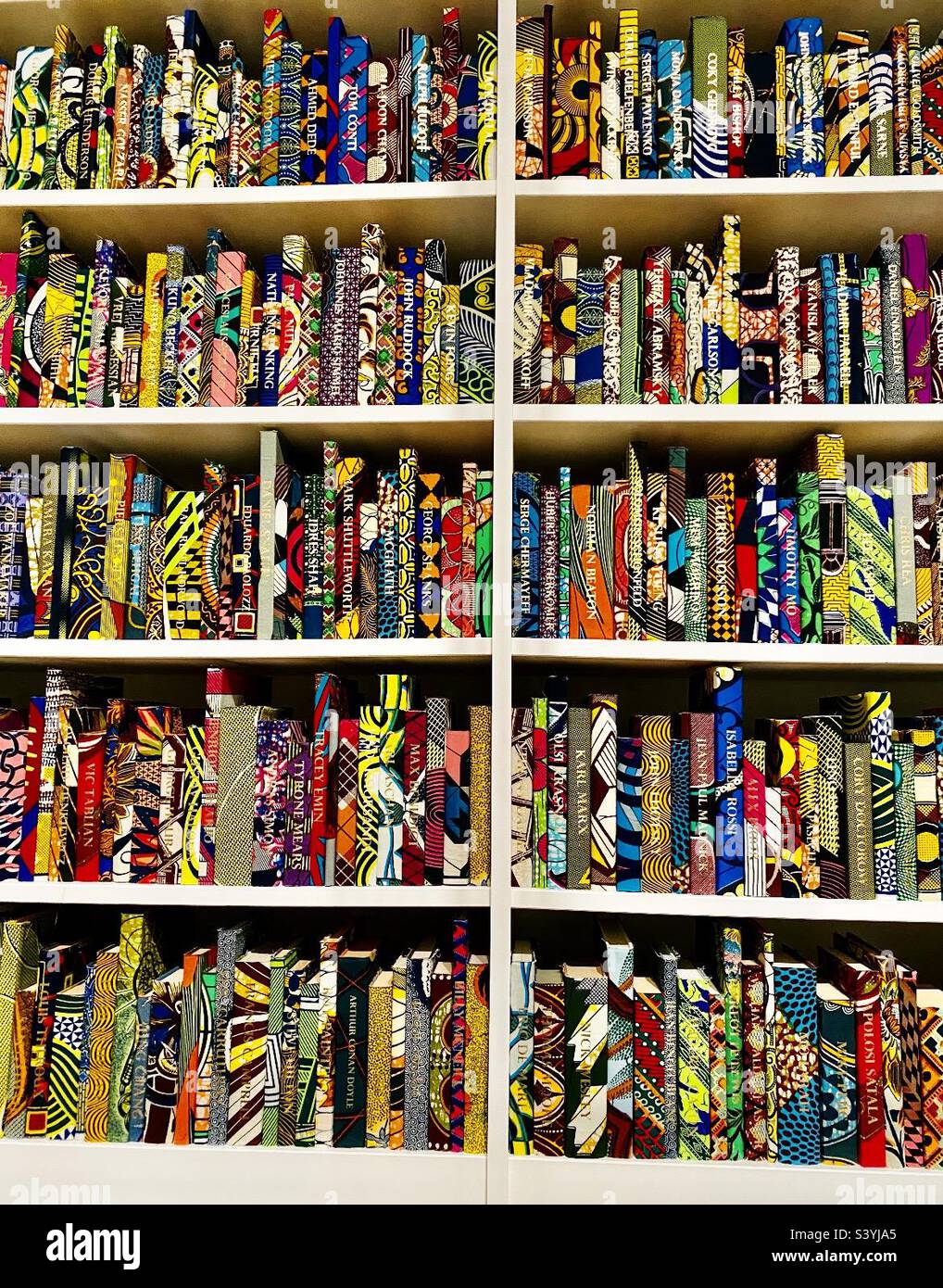 Tate Modern “The British Library 2014” by Yinka Shonibare. A display of 6,328 hardback books individually covered in colourful ‘Dutch wax print’ fabric with gold leaf on the spines of 2,700. Stock Photo