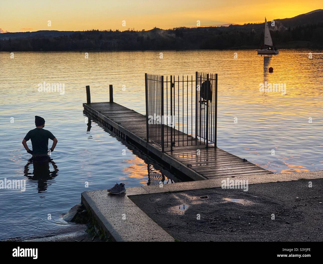 Wild swimming in Lake Windermere with a passing boat at dusk, Cumbria Lake District - Smartphone Captured Stock Image