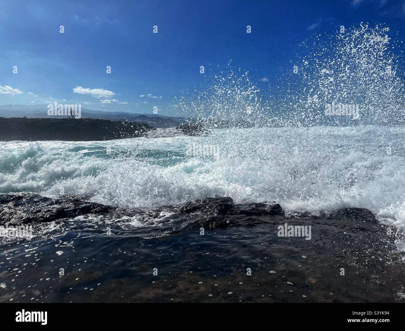 Sea spray with fisherman in the distance - Playa del Confital, Las Palmas, Gran Canaria - Smartphone Captured Stock Image