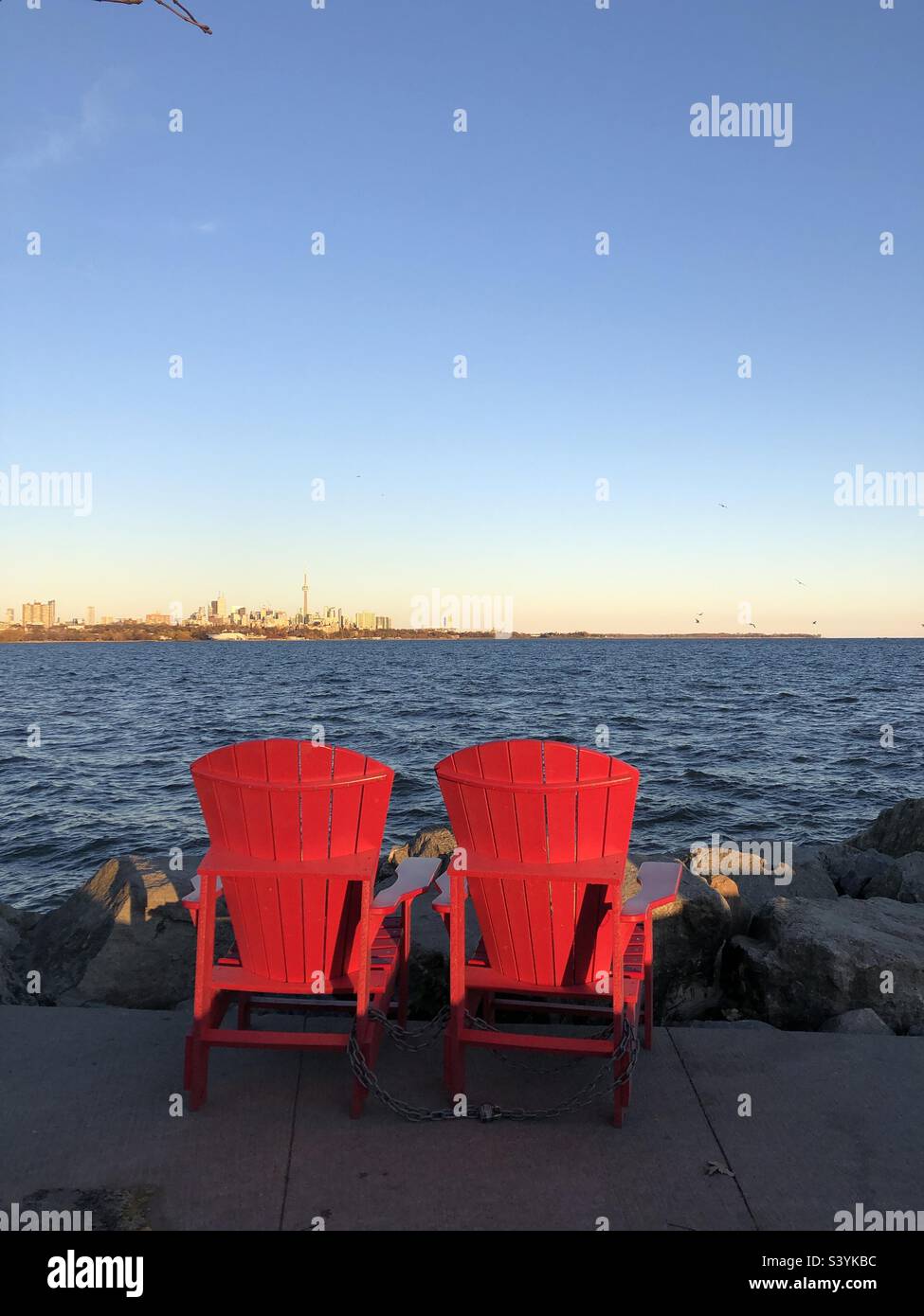 Red Muskoka chairs overlooking Lake Ontario in Toronto, Canada Stock