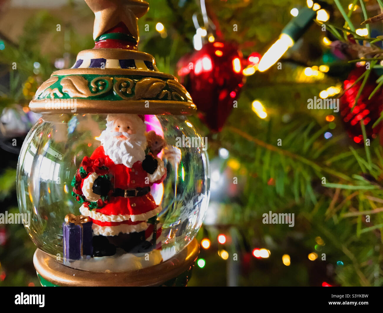 Close up view of a Christmas ornament with Santa Claus on a Christmas Tree surrounded by Christmas lights. Stock Photo