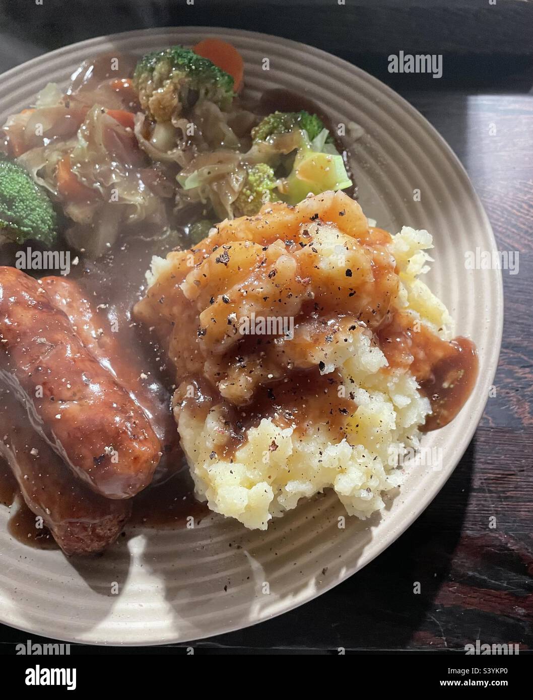 Steaming hot sausages, mashed potato, vegetables and gravy. Sausages
