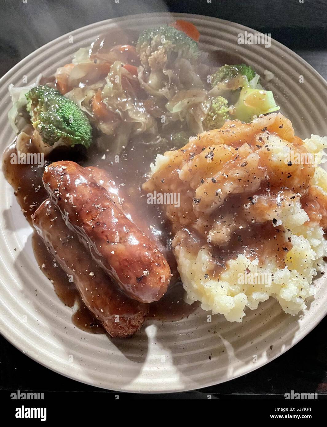 Steaming hot sausages, mashed potato, vegetables and gravy. Sausages