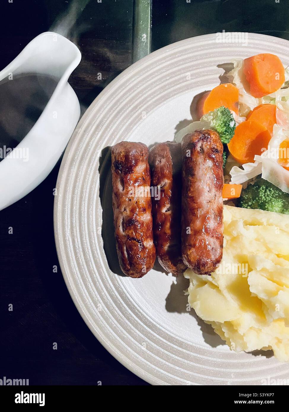 Sausage and mash with vegetables and gravy. Sausages cooked in an air