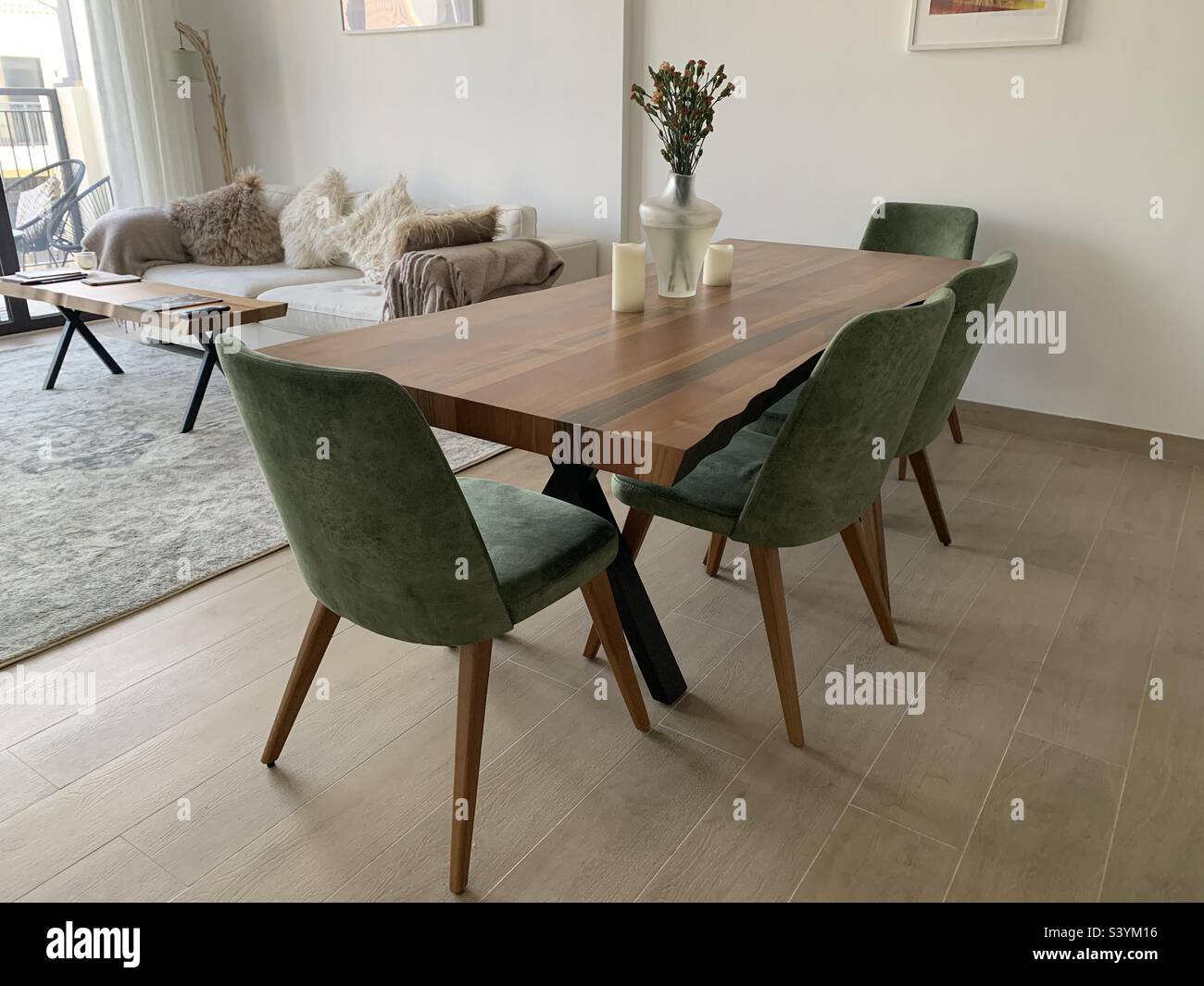 Stylish wooden dining table with green chairs in an open plan living room - Smartphone Captured Stock Image