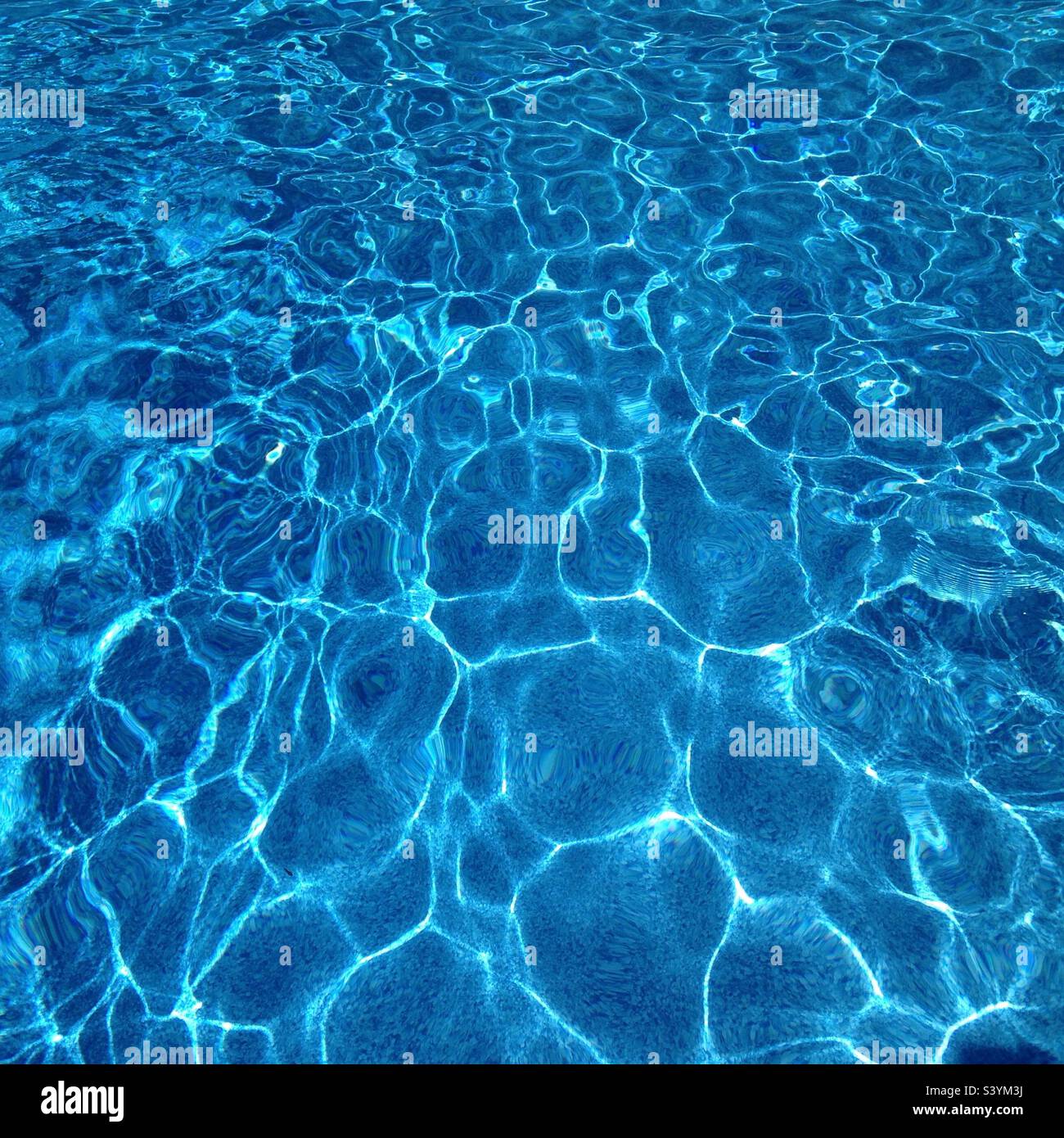 Blue pool water with a fun pattern created by the sunlight Stock Photo