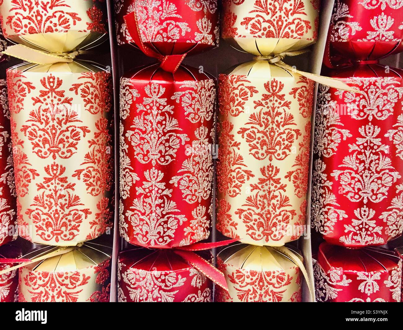 Red and gold patterned Christmas crackers in a box Stock Photo
