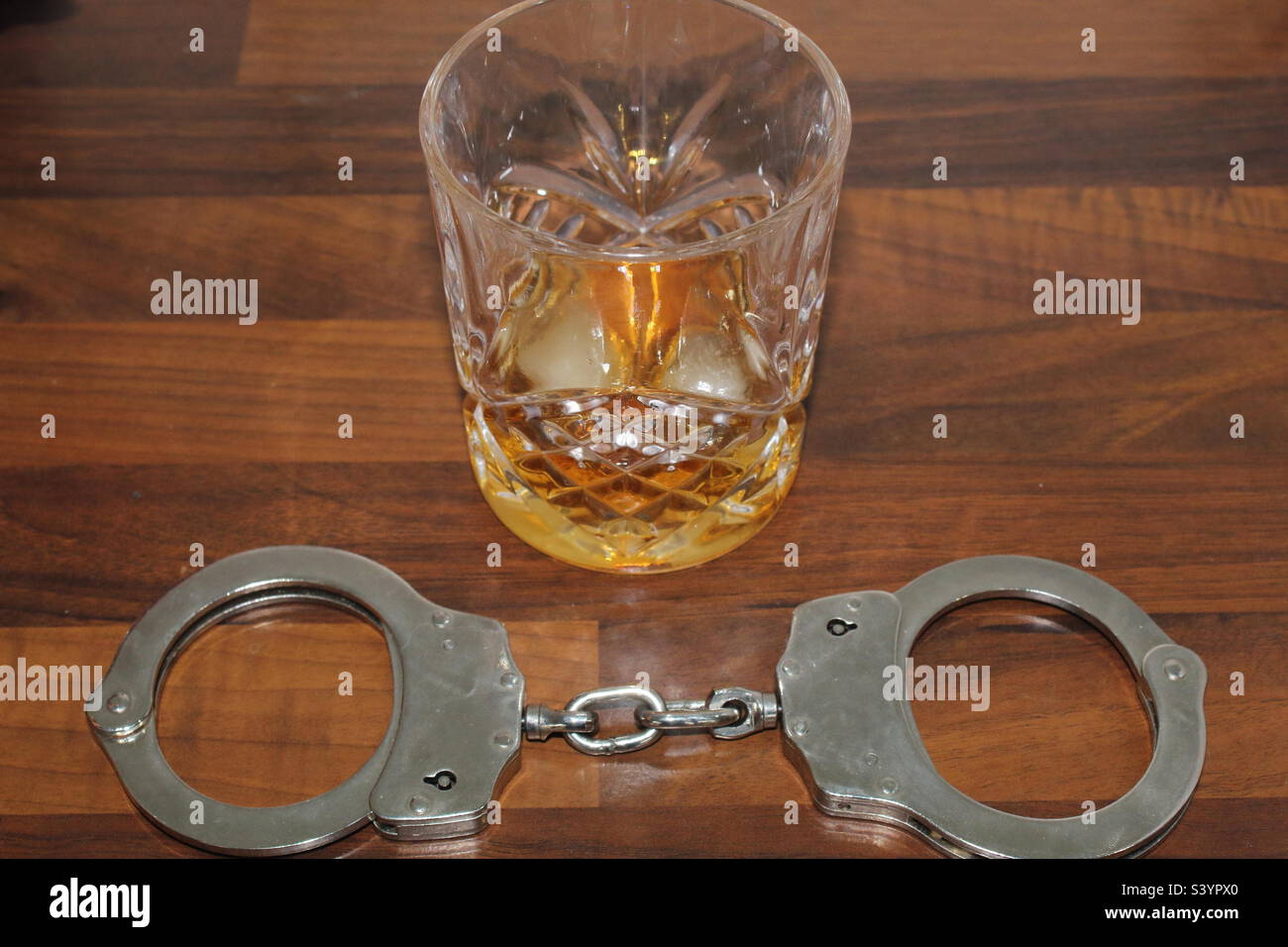 Handcuffs and whisky on a desk - Smartphone Captured Stock Image