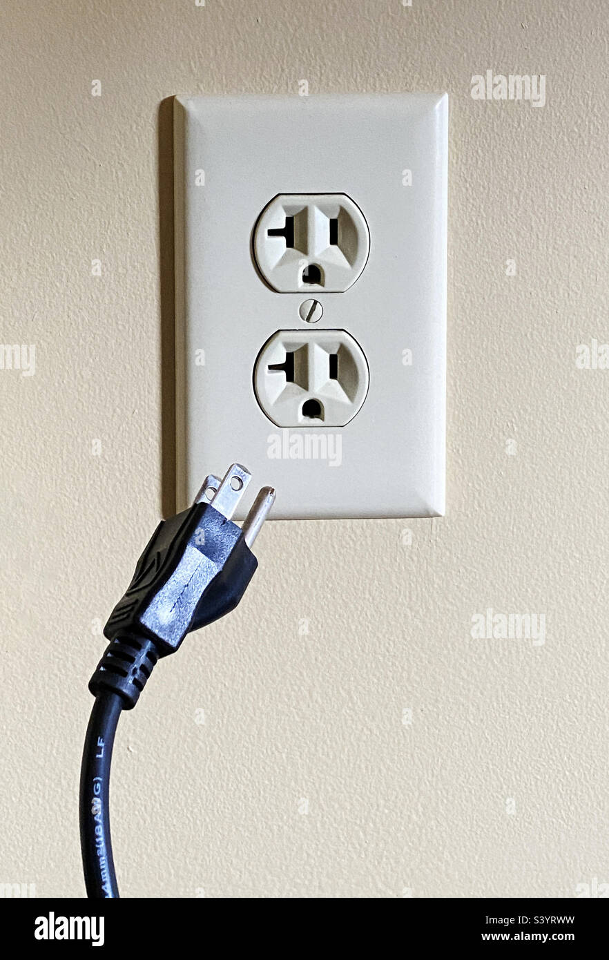 Electrical cord unplugged from electrical outlet in the United States. Stock Photo