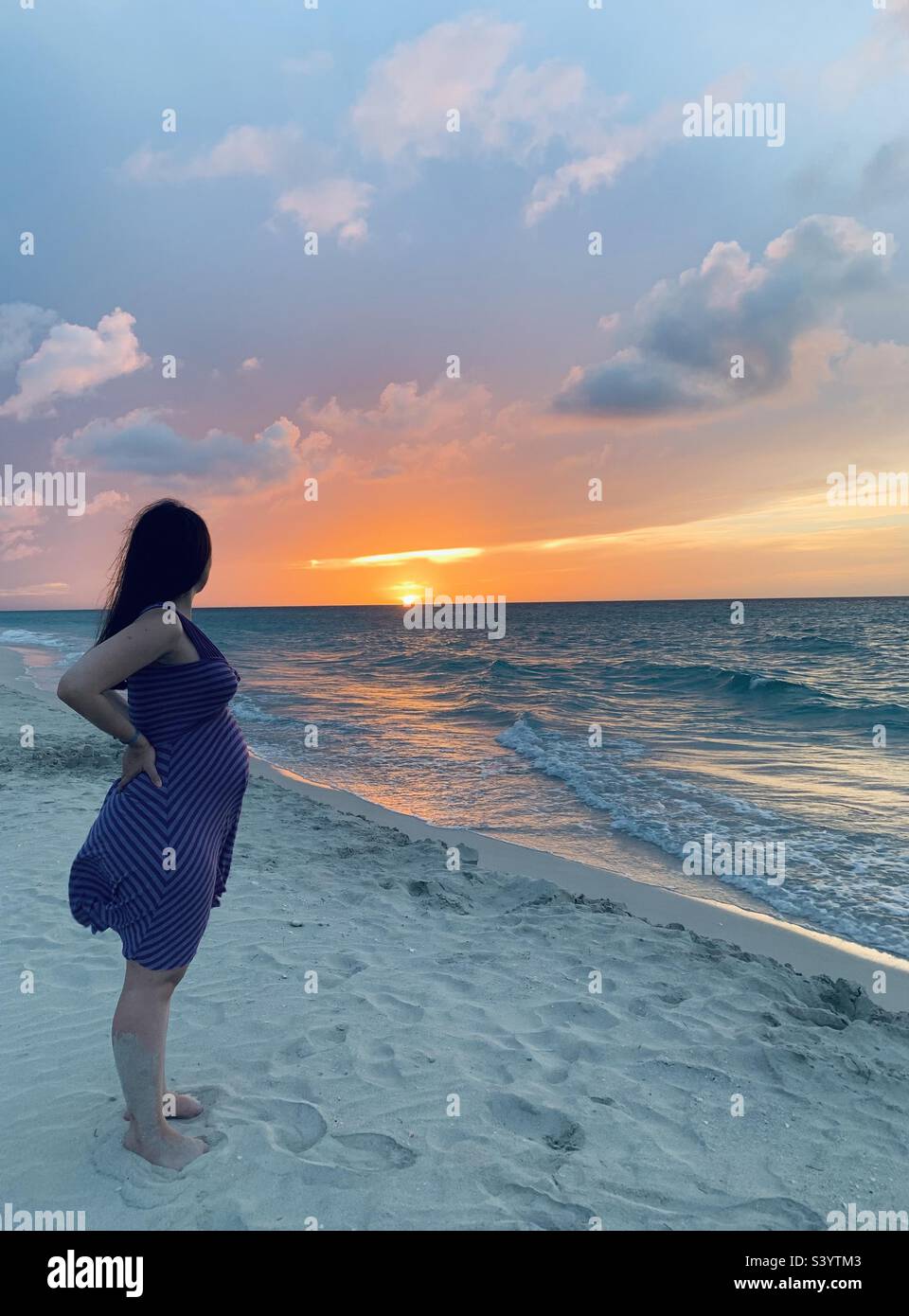pregnant woman contemplating the sunset by the ocean. varadero, cuba - Smartphone Captured Stock Image