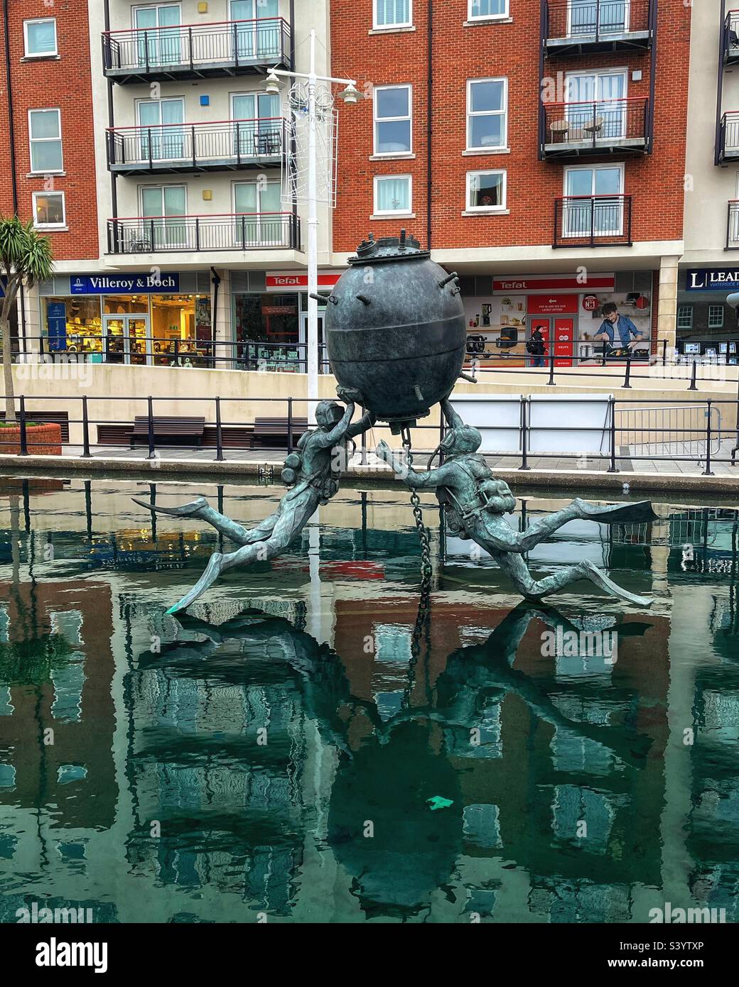 Vernon Mine Warfare & Diving Monument by sculptor Mark Richards FRSS comprises a moored mine with two attendant Clearance Divers seen Gunwharf Quays in Portsmouth, the former site of HMS VERNON Stock Photo