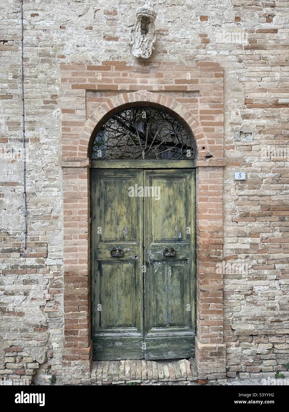 Old door with coat of arms in the medieval village of Lapedona, Marche region, Italy - Smartphone Captured Stock Image