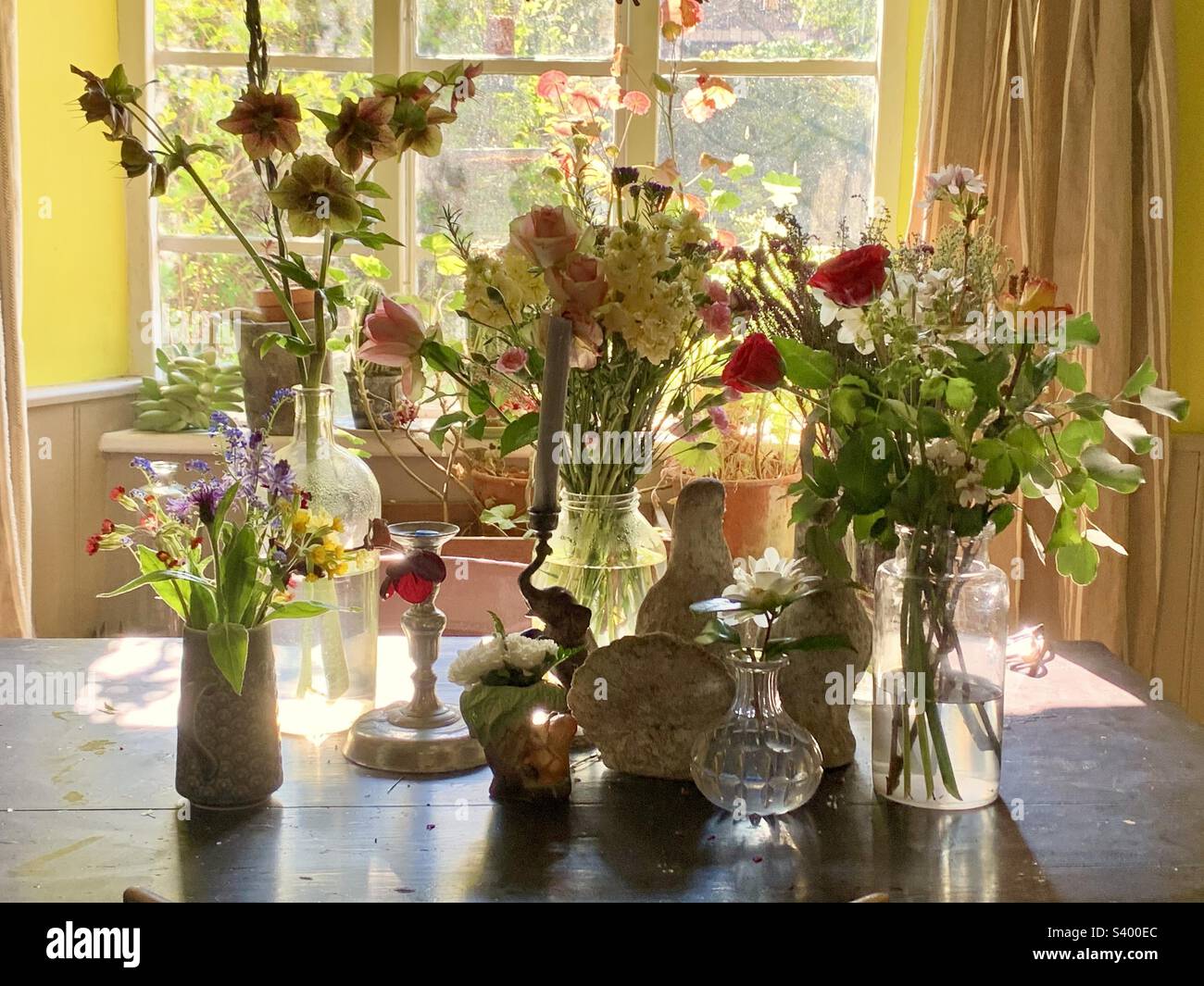 Perfect English country cottage kitchen table with beautiful cut flowers against a bright window in spring, Somerset England Stock Photo