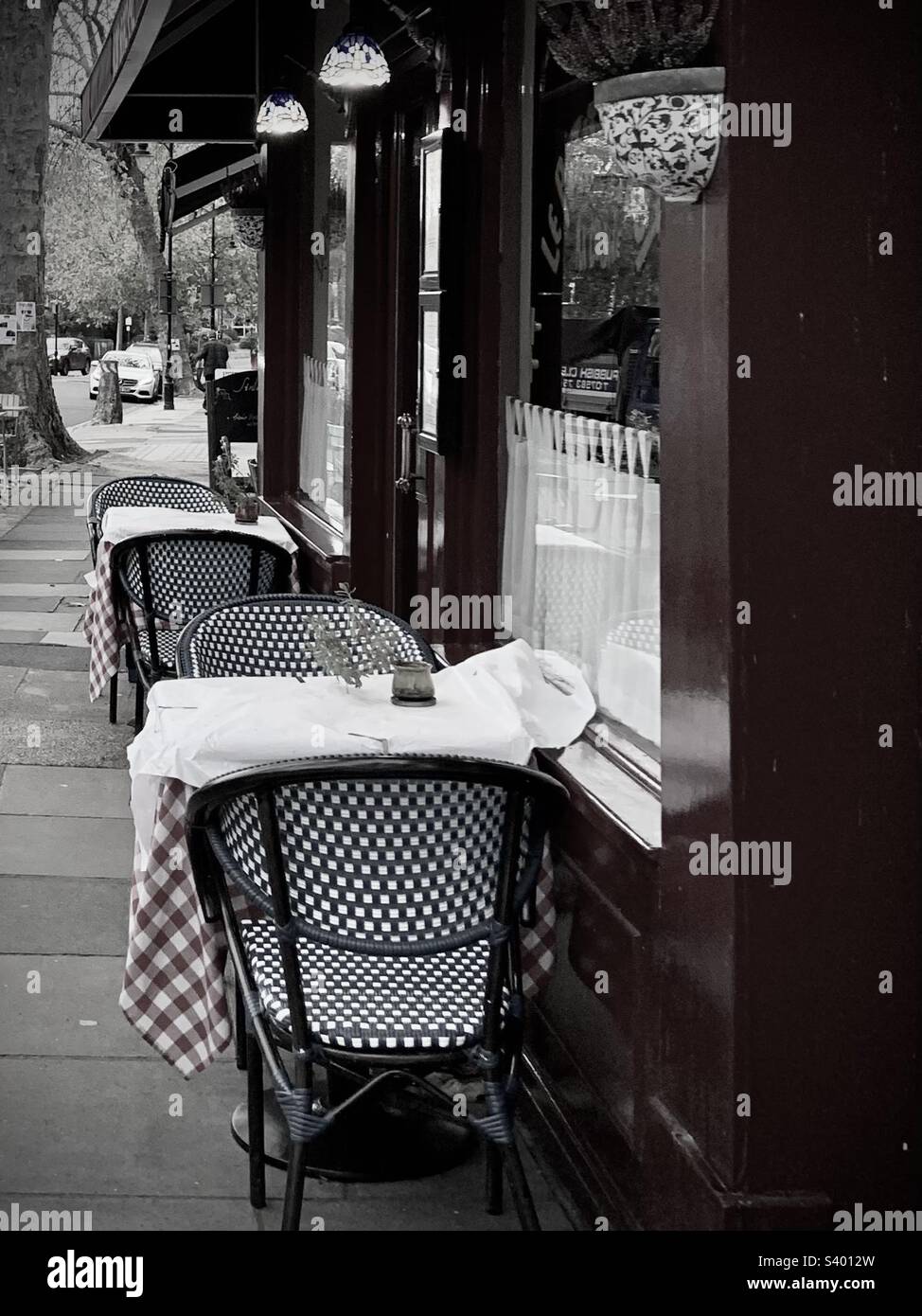 An Italian restaurant cafe with tables outside on the pavement. Checkered table cloths and wicker chairs Stock Photo