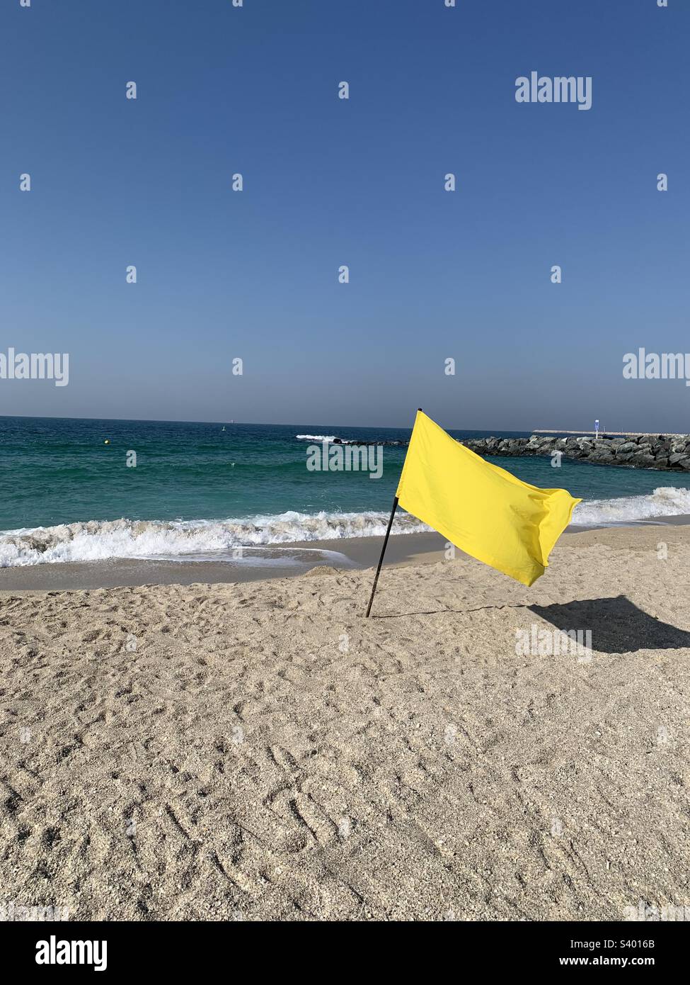 Yellow flag and its shadow on a beach in Dubai, United Arab Emirates