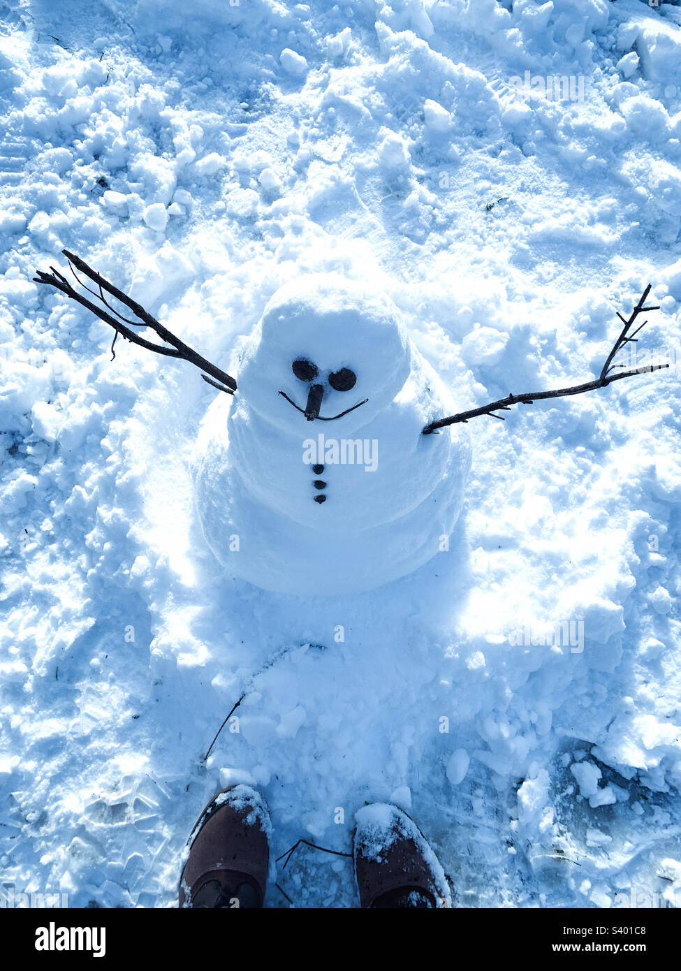 A person standing in front of snow man 2022 - Smartphone Captured Stock Image