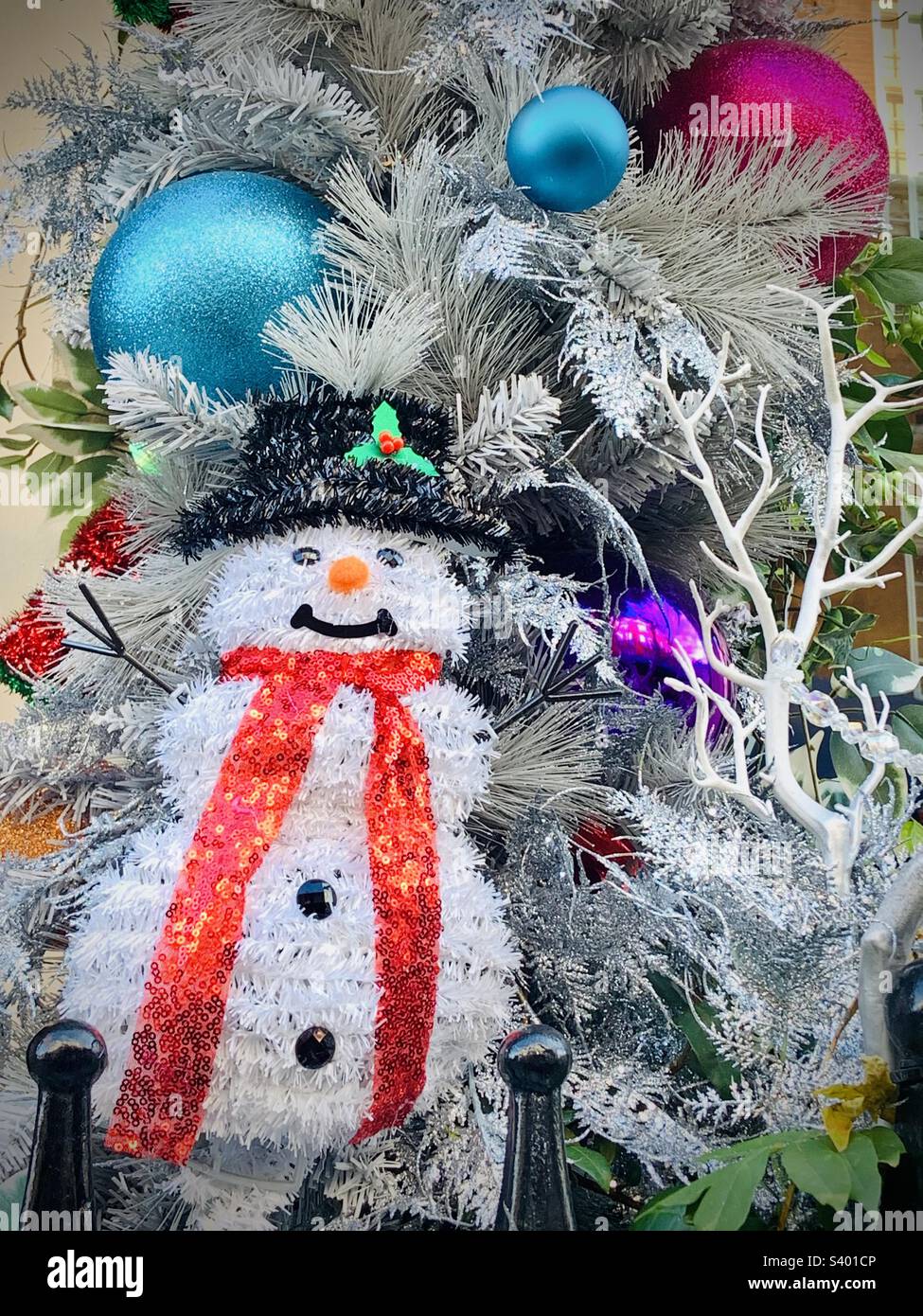 Silver Christmas tree with decorations. Baubles and a snowman hanging from the tree Stock Photo