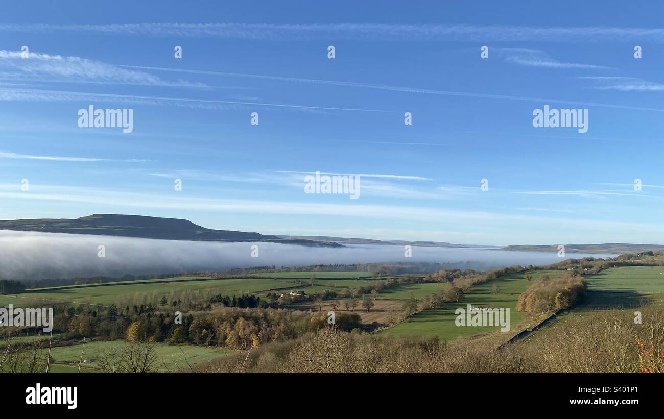 A temperature inversion in Wensleydale, North Yorkshire with Penhill rising above the fog filled Dale below Leyburn, North Yorkshire - Smartphone Captured Stock Image