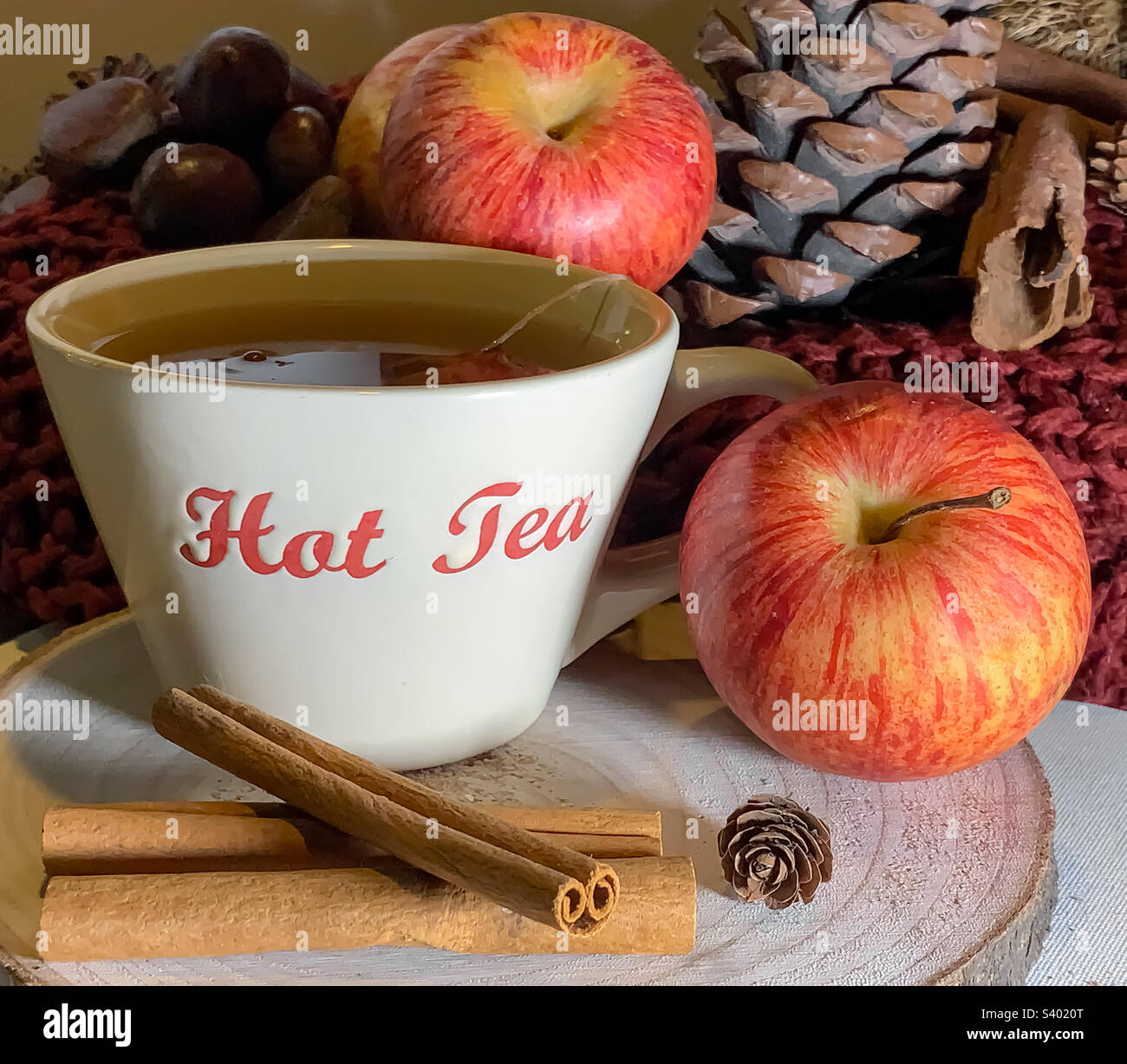 Apple & Cinnamon tea, shown with fruit, spice, pinecones and nuts on a wooden platter Stock Photo
