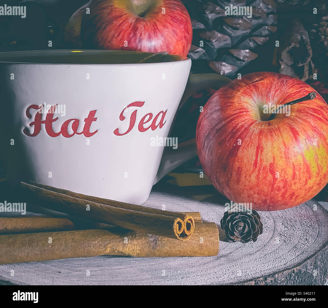 Apple & Cinnamon tea, shown with fruit, spice and pinecones on a wooden platter Stock Photo