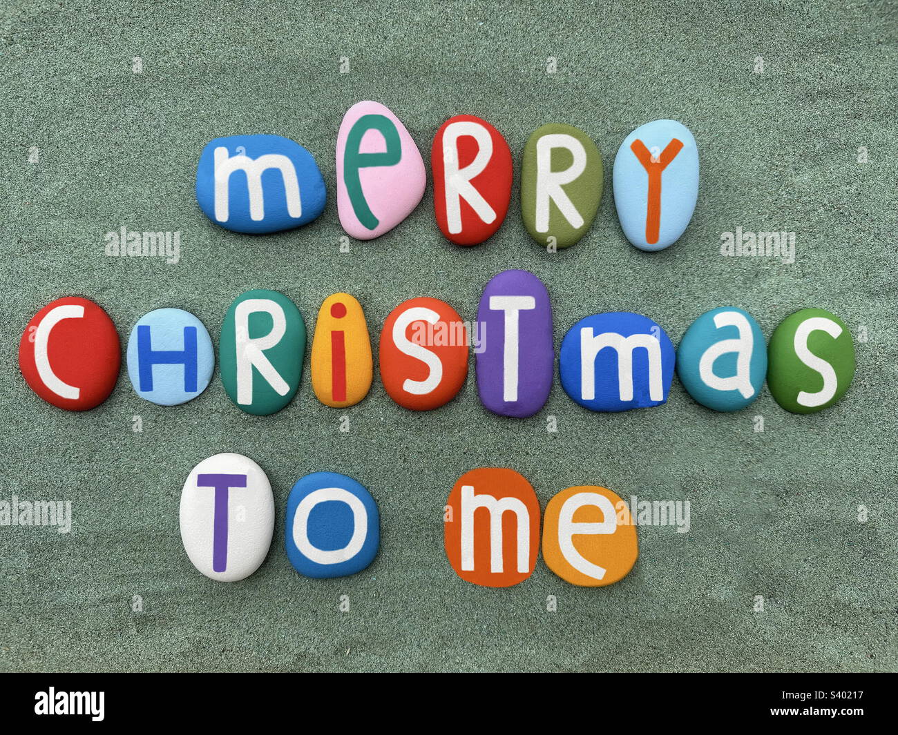 Merry Christmas to me, creative text composed with hand painted multi colored stone letters over green sand - Smartphone Captured Stock Image